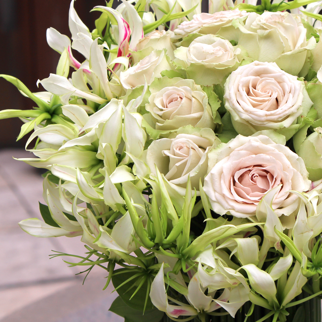 「愛」を象徴するベージュのバラと、躍動感のある白いグロリオサが織りなす繊細なテクスチャー