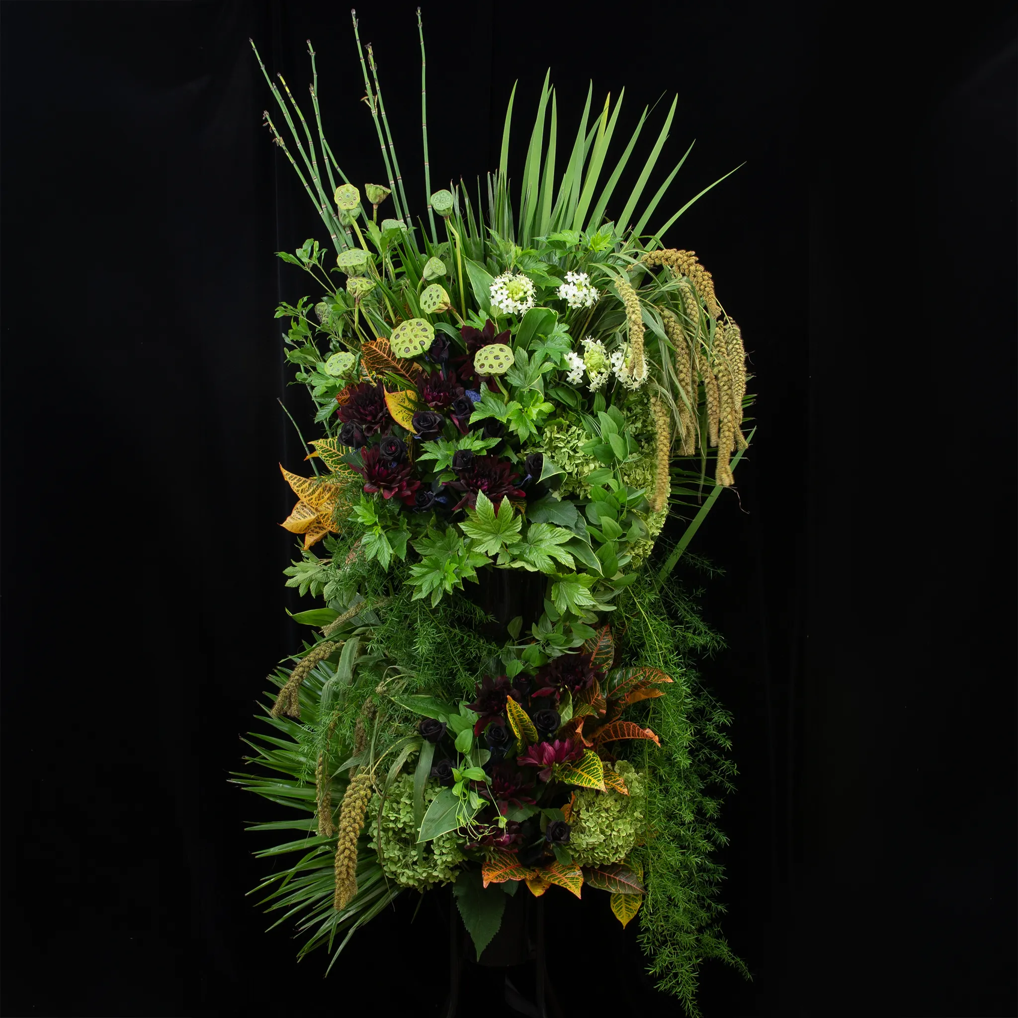 東京23区限定配送。豊かなグリーンとダークトーンの花々が織りなす、立体的で洗練されたデザインのスタンド花